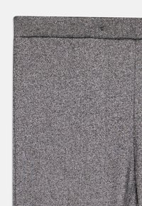 Leggings de tecido cinzento com acabamento texturizado, apresentando uma cintura lisa e um brilho subtil por todo o material, sem padrões visíveis.