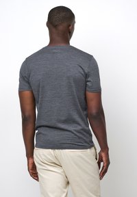 Grå kortärmad t-shirt med en slät textur, med rund halsringning och en figurnära design på baksidan, kombinerad med ljusbeige byxor.