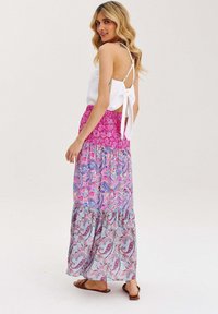 Dlouhé, splývavé šaty s bílým, bezramínkovým vrškem. Sukně má růžové, modré a paisley vzory. Nastavitelné ramínka a zavazování vzadu.