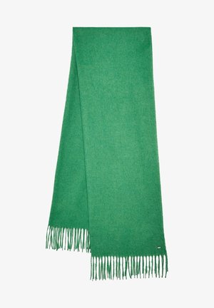 Bufanda de lana verde suave doblada a lo largo con extremos con flecos y una pequeña etiqueta metálica rectangular cerca del borde inferior.