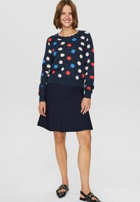 Mornarska jopica z multikolornih pikami, z robom v obliki školjke, v kombinaciji s temno mornarsko krilom v obliki zvona. Črne čevlje z okrasnimi studenci.