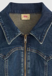 Giacca in denim blu con zip, dotata di colletto a punta, cuciture arancioni e etichetta del marchio sul collo. Il tessuto presenta una leggera scoloritura.