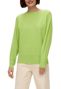 Hellgrüner, gerippter Pullover mit weiter Rundhalsausschnitt und langen Ärmeln, der über ein strukturiertes Strickmuster und eine lockere Passform verfügt. Kombiniert mit cremefarbenen Hosen.