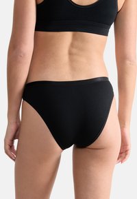 Schwarze Baumwoll-Bikini-Slips mit glatter Textur, einfachem Design und kontrastierendem schwarzen elastischen Bund.