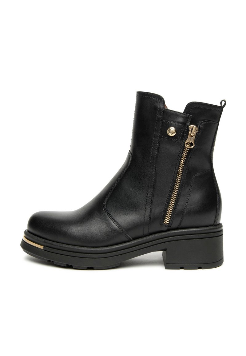 Botte chelsea en cuir noir avec un petit talon carré, fermeture éclair sur le côté et détails en doré. Texture lisse et design épuré avec des coutures marquées.
