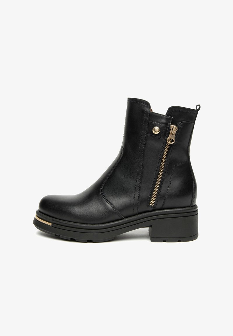 Botte chelsea en cuir noir avec un petit talon carré, fermeture éclair sur le côté et détails en doré. Texture lisse et design épuré avec des coutures marquées.