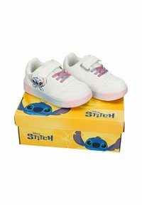 Baskets blanches pour enfants avec des lacets roses et violets, impression du personnage Stitch sur les côtés, placées sur une boîte à chaussures jaune Disney Stitch.
