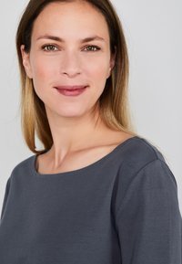 Grijs, shirt met ronde hals, gemaakt van zachte stof, met een ontspannen pasvorm, een gladde textuur en subtiele stiksels langs de halslijn.