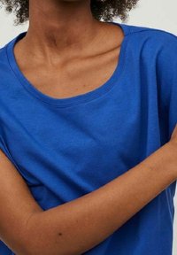 Modré tričko s krátkým rukávem vyrobené z měkké látky, s širokým kulatým výstřihem a uvolněným střihem, s hladkým povrchem bez vzorů.