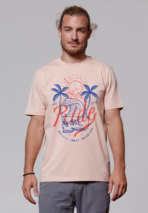 Helles, rosa Baumwoll-T-Shirt mit einem Grafikdesign von einer Sonne, einem Surfer, Wellen und Palmen in Blau und Rot. Kurze Ärmel, Rundhalsausschnitt.