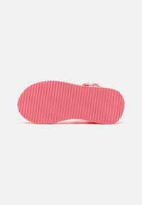Rosa gummisandal sula med räfflad textur, rund form och lätt upphöjda kanter, designad för grepp och stabilitet.