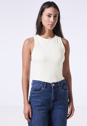 Top senza maniche di un giallo chiaro con scollatura rotonda, decorato con piccole perline, abbinato a jeans in denim blu scuro a vita alta.