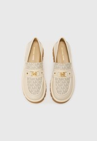 Ανοιχτό μπεζ slip-on παπούτσια με πλεγμένο σχέδιο MK, χρυσό ένθετο υλικού και υφασμένο καουτσούκ σόλας για πρόσφυση και άνεση.