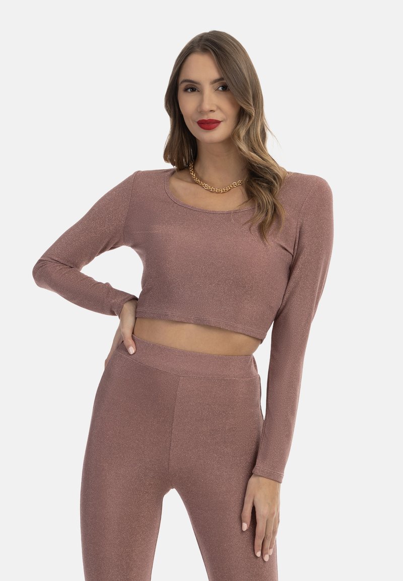 Rózsaarany fémes anyagú crop top és leggings szett. Hosszú ujjú, kerek nyakkivágású és rugalmas fazonú. Sima felület, finom fényű.