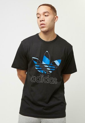 Sort bomulds T-shirt med et blåt og sort stribet trefoil-logo med teksten "adidas" nedenfor. Korte ærmer og rund hals.