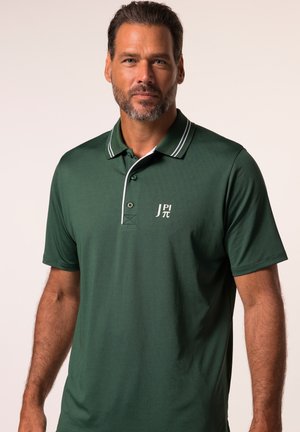 Polo shirt in donkergroen met een witte accent op de kraag. Voorzien van een sluiting met twee knopen en een logo op de linkerborst. Soepele stofstructuur.