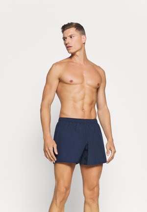 Shorts de bain bleu marine avec une taille élastique, coupe droite et tissu léger, arrivant au-dessus du genou. Sans motifs ni accents.