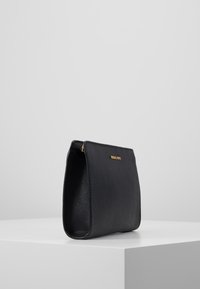 Borsa a mano nera in pelle con finitura testurizzata, dotata di logo dorato e chiusura con zip. Forma rettangolare e design strutturato.