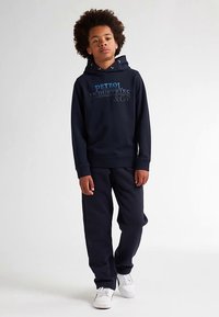 Felpa con cappuccio blu navy con stampa del logo azzurro chiaro, abbinata a pantaloni della tuta blu navy coordinati. Tessuto liscio, design casual e sneakers bianche.