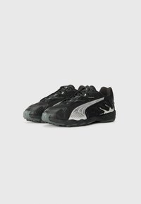 Zapatillas deportivas negras con parte superior de malla y sintético, que presentan acentos plateados, superposiciones texturizadas y una suela de goma con patrones de textura.