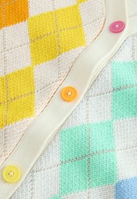 Sweter dzianinowy z geometrycznym wzorem w żółte, zielone i pomarańczowe kwadraty. Z przodu ozdobiony czterema przyciskami w różnych kolorach.