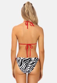Czerwony bikini z halterem, z regulowanymi wiązaniami, połączone z niskimi czarno-białymi majtkami w pasek zebra. Gładka tekstura, minimalistyczny design z ograniczonymi zakryciami.