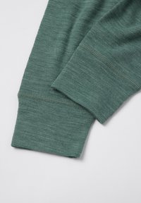 Twee gevouwen groene mouwen van een langemouwen shirt met zichtbare stiksels op een effen witte achtergrond.