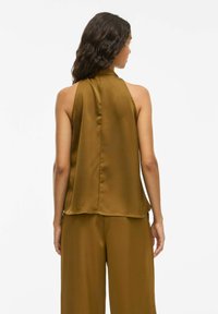 Top in satin con scollo a halter di un ricco verde oliva, caratterizzato da un collo alto e un design fluente, con schiena aperta e una texture liscia.