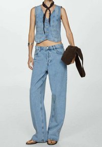 Ensemble jean composé d'un gilet en denim et d'un jean à jambes larges en bleu clair. Le gilet est doté de boutons et d'une coupe courte. Les accessoires comprennent un foulard noir autour du cou et une veste marron.