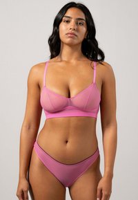 Rosa Bralette und passendes Tanga-Set aus glattem Material; verfügt über verstellbare Träger, eine dezente Naht und minimalistisches Design.