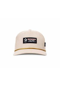 Beige corduroy cap with a black rectangular patch displaying a logo and text. Features a gold accent band along the brim. Structured shape.