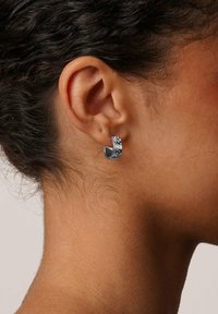 Silverfärgade hoopsringar med en texturerad yta och sm�å klara ädelstenar, som har en böjd design som sveper runt örsnibben.