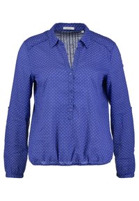 Blusa azzurra con bottoni, maniche lunghe, scollatura a V e motivo triangolare bianco. Presenta polsini arricciati e una vita rilassata.