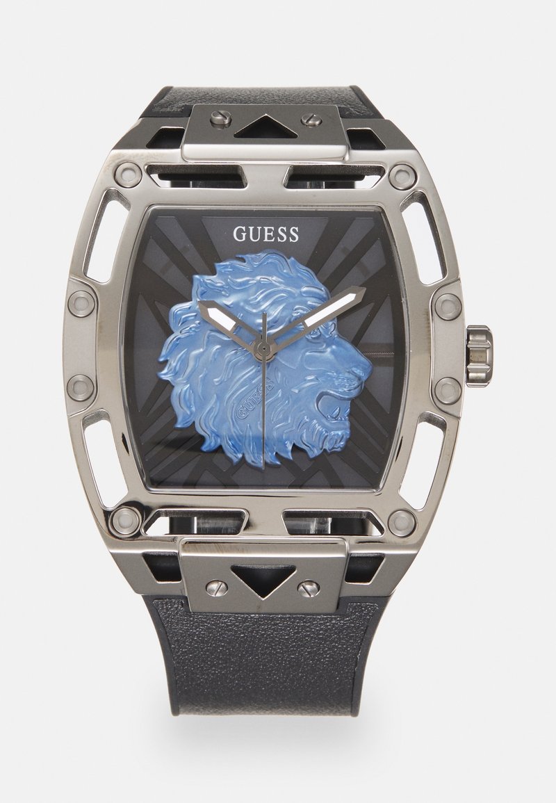 Quadratische silberne Uhr mit schwarzem Armband, blauem Löwenkopf-Design auf schwarzem Zifferblatt, silbernen Zeigern und "GUESS" Logo oben in der Mitte.