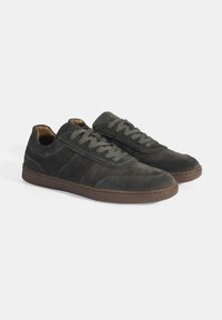 Gray suede sneakers with a low profile, round toe, and matching laces. Textured panels and brown rubber soles add contrast and grip.