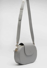 Borsa a tracolla grigia in ecopelle con forma arrotondata, chiusura con zip, patta e accessori in metallo dorato. Inclusa tracolla regolabile.