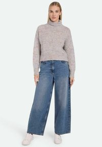 Light gray knit turtleneck sweater with a cropped design, paired with wide-leg blue denim jeans and white sneakers. Textured fabric with colorful flecks.