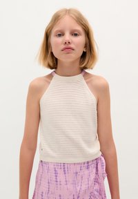 Light beige knitted halter top with a textured pattern and purple straps, paired with a pink tie-dye skirt featuring soft folds and draping.