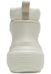 Botas Crocs blancas con forma redondeada, parte superior acolchada, suela de goma texturizada con pequeños puntos y una pestaña trasera para facilitar el uso.