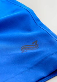 Niebieska tkanina sportowa o gładkiej fakturze, z czarnym logo z zakrzywionymi liniami po lewej stronie oraz wzmocnionymi szwami.