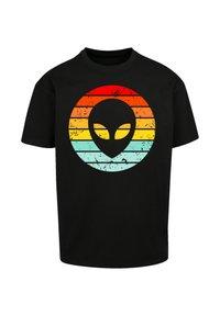 Schwarzes T-Shirt mit einem runden Grafikdesign, das ein retro gestreiftes Muster in Rot, Orange, Gelb und Blau zeigt, mit einer Silhouette eines Alienkopfes in der Mitte.