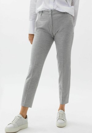 Pantalon gris en matériau doux avec une coupe ajustée, doté de poches avant et d'une texture lisse, associé à des baskets blanches.