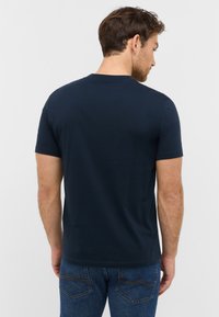 T-shirt bleu marine à manches courtes en coton, doté d'un col rond classique et d'une coupe régulière, avec une texture lisse et un minimum de détails.