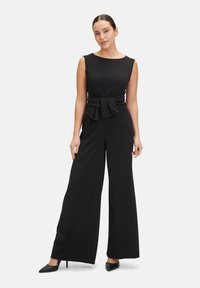 Black jumpsuit with a fitted bodice, wide-leg pants, and a waist bow detail. Smooth fabric and sleeveless design.