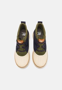 Blauwe en groene sneakers met crèmekleurige rubberen zolen, textielstof, vetersluiting en bruine leren accenten op de tong.