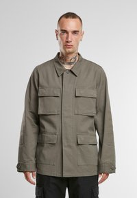 Chaqueta verde militar fabricada en algodón, con cuello tipo solapa, cuatro bolsillos frontales y adornos de botones en las mangas.