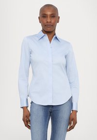 Svjetloplava košulja s dugim rukavima, šiljastim ovratnikom, prednjim dugmadi i prilagođenim dizajnom. Glatka pamučna tkanina s suptilnim sjajem.