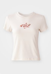 Korte mouwen, lichtbeige T-shirt van katoen, met een rode "nike" logo en decoratieve elementen erboven. Klassieke ronde hals.
