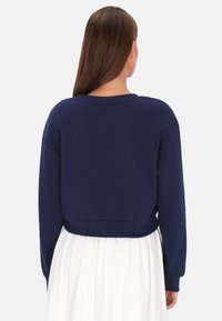 Tengerészkék, rövidített felső részű pulóver hosszú ujjakkal, bordázott alsó szegéllyel és kerek nyakkivágással. Texturált anyag, minimalista design.