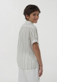 Camicia bianca a maniche corte con strisce verticali grigie, con polsini abbottonati e colletto casual, esposta su uno sfondo neutro.